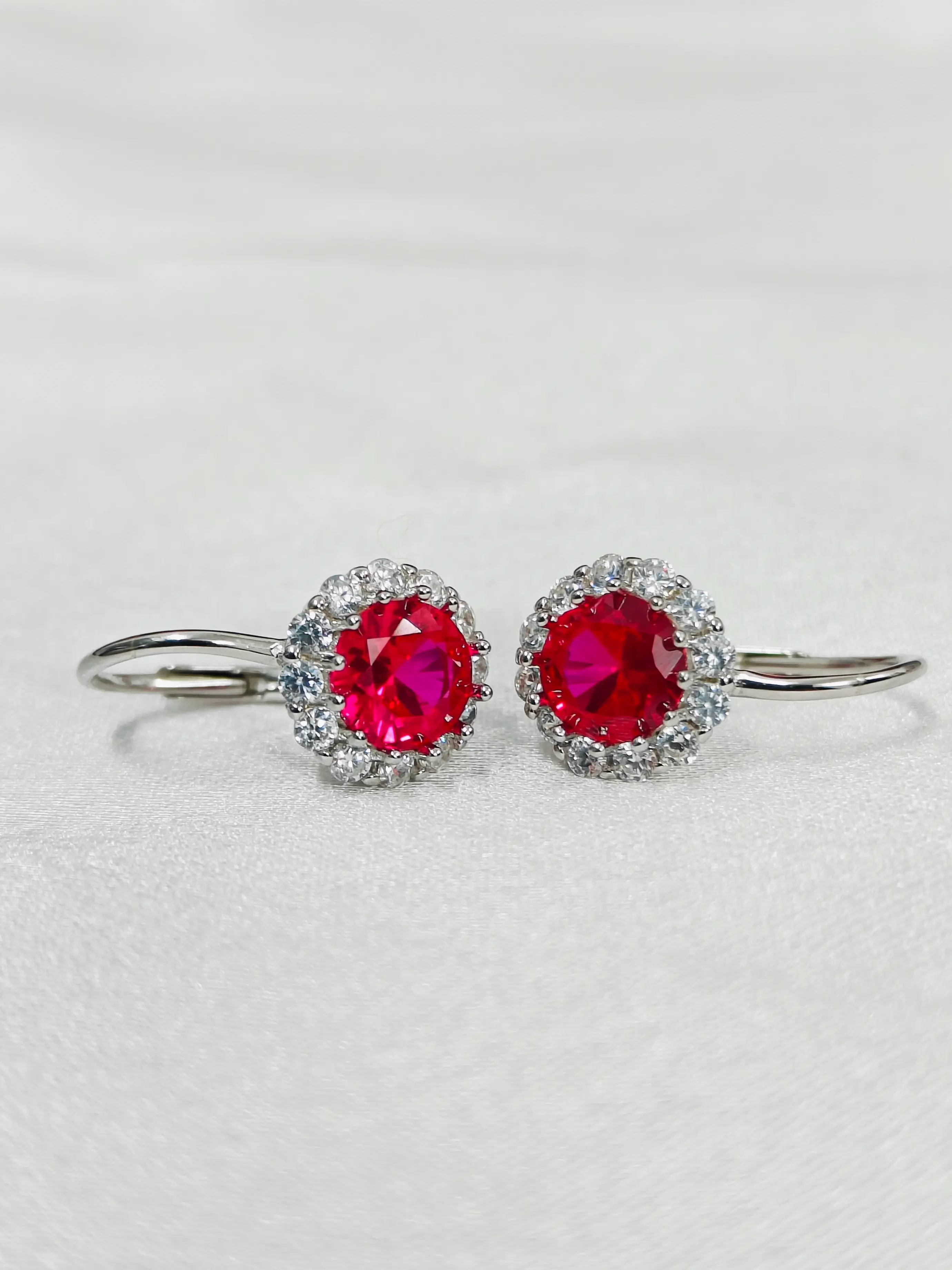 Pair of earrings with red gemstones on a light gray background